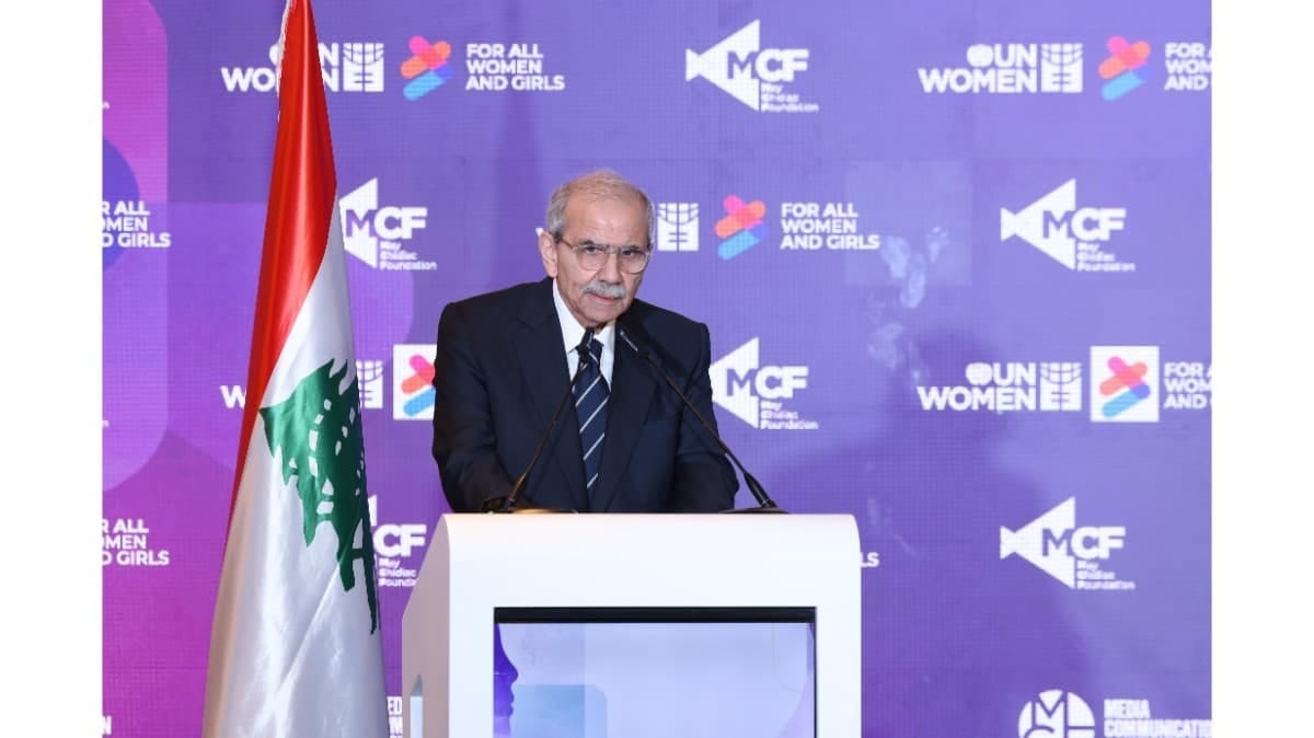 Lebanese Prime Minister Nawaf Salam speaking at a podium during the Women on the Front Lines conference, with the Lebanese flag visible on the left.