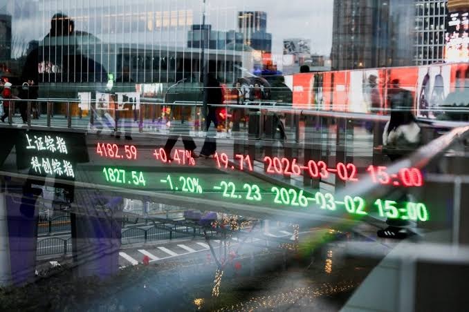 مؤشرات وأسعار أسهم باللونين الأحمر والأخضر تنعكس على واجهة زجاجية وسط حركة المارة في مدينة آسيوية.